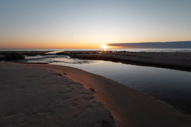 Su gibi ayna ile Baltık Denizi 'nde kırmızı canlı günbatımı-Veczemju Klintis, Letonya-13 Nisan, 2019