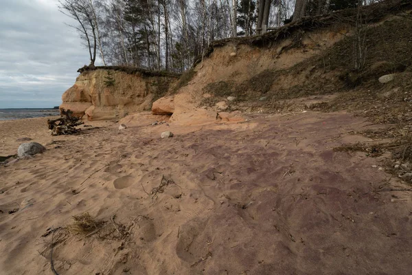 Vápencová pláž v Baltském moři s nádherným písečnými vzory a živými červenými a oranžovými barvami-turistické spisy na zdech a skalách a písku-Veczemju Klintis, Lotyšsko – 13. dubna 2019 — Stock fotografie