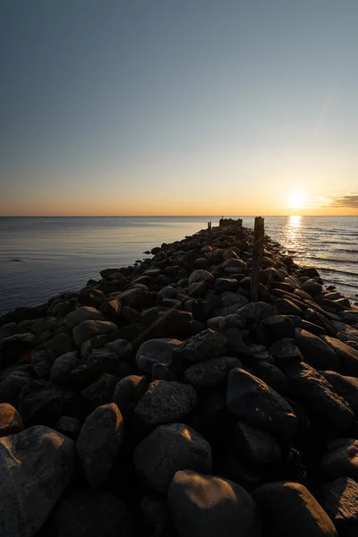 Boulder plaży molo zachód słońca z żywych kolorów czerwonych i pomarańczowych na Morzu Bałtyckim-Tuja, Łotwa-13 kwietnia 2019 — Zdjęcie stockowe