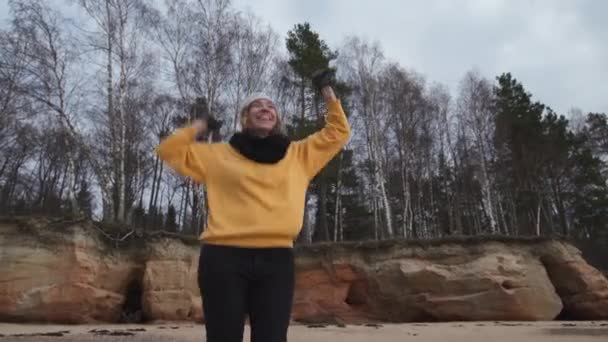 Gelukkig jonge mode verslaafd vrouw doet sport op het strand in de koude lente weer-Veczemju Klintis, Letland-13 april 2019 — Stockvideo