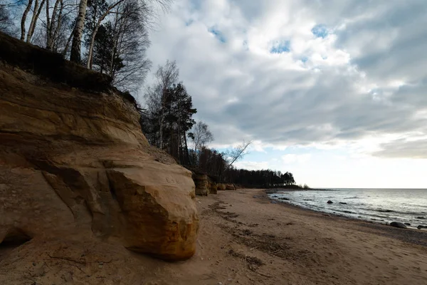 Wapienne plaży nad Morzem Bałtyckim z pięknym wzorem piasku i żywe czerwony i pomarańczowy kolor-pisma turystyczne na ścianach i kamieniach i piasku-Veczemju Klintis, Łotwa-13 kwietnia 2019 — Zdjęcie stockowe