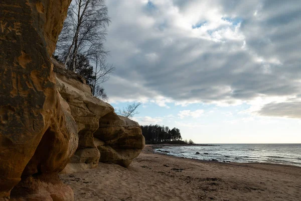 Spiaggia calcarea sul Mar Baltico con un bellissimo motivo di sabbia e un colore rosso vivo e arancione - Scritti turistici sulle pareti e rocce e sabbia - Veczemju Klintis, Lettonia - 13 aprile 2019 — Foto Stock