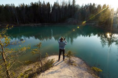 Genç adam seyahat fotoğrafları çekiyor - Letonya 'da güzel turkuaz göl - Baltık devletlerinde Meditirenyen tarzı renkler - Lackroga ezerleri
