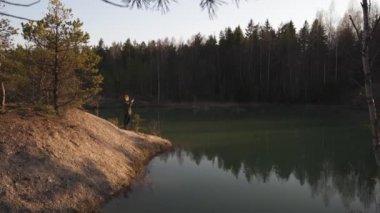 Genç bir kadın, Letonya 'nın Baltık eyaletlerindeki turkuaz renkli gölün telefon uygulamasını kullanarak fotoğraf çekiyor.