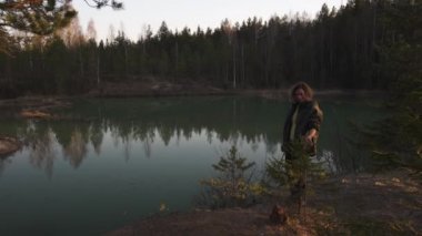 Genç bir kadın, Letonya 'nın Baltık eyaletlerindeki turkuaz renkli gölün telefon uygulamasını kullanarak fotoğraf çekiyor.