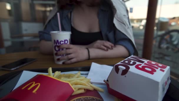 RIGA, LATVIA - 22 DE ABRIL DE 2019: Mujer joven comiendo en el restaurante de comida rápida Mcdonalds - Big Mac, papas fritas medianas y Coca-Cola — Vídeos de Stock