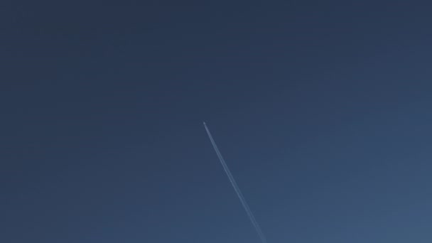 Blauwe heldere hemel met een vliegtuig dat over het hele frame vliegt en een mooi parcours achterlaat-ideaal voor advertentie advertentie voor reisbedrijf — Stockvideo