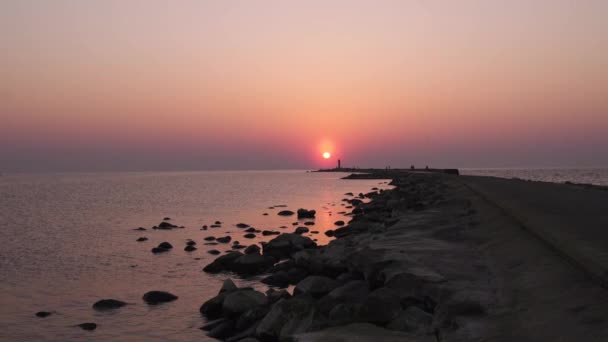 地平線と澄んだ空に近い大きな太陽と日没の土壇場の間に灯台 — ストック動画