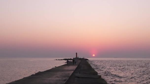 Farol durante um último minuto de pôr do sol com um grande sol perto do horizonte e céu limpo — Vídeo de Stock