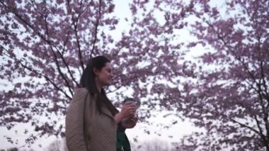 Genç bir kadın çiçek açan sakurasıyla parkta yürüyor. Kâğıt bardaktan kahve içiyor ve rüya görüyor.
