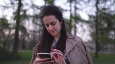 Arka planda sakura çiçeği olan telefonunu kullanan genç bir kadın.