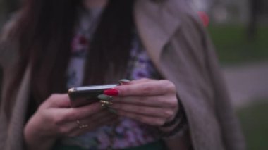 Arka planda sakura çiçeği olan telefonunu kullanan genç bir kadın.