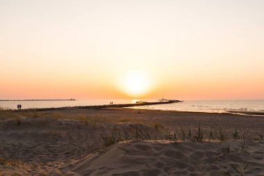 Ufuk ve berrak gökyüzüne yakın büyük bir güneş ile gün batımının son dakikasında deniz feneri