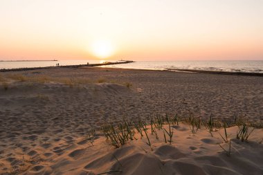 Ufuk ve berrak gökyüzüne yakın büyük bir güneş ile gün batımının son dakikasında deniz feneri