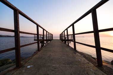 Ufuk ve berrak gökyüzüne yakın büyük bir güneş ile gün batımının son dakikasında deniz feneri