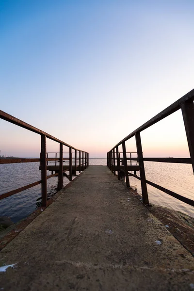 Vuurtoren tijdens een laatste minuut van zonsondergang met een grote zon dicht bij de horizon en heldere hemel — Stockfoto