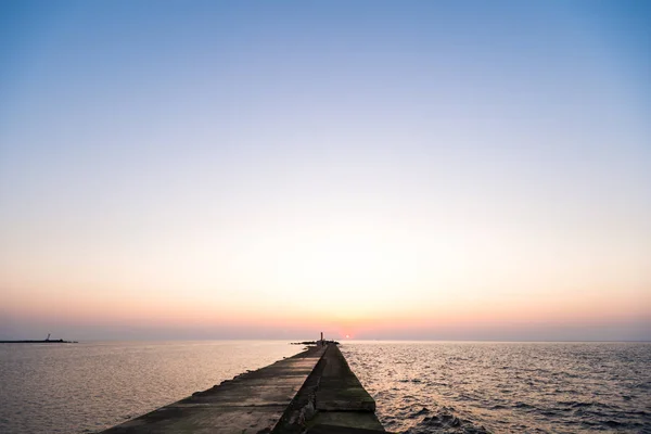 Ufuk ve berrak gökyüzüne yakın büyük bir güneş ile gün batımının son dakikasında deniz feneri — Stok fotoğraf