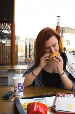 Marupe, Letonya - 22 Nisan 2019: Gün batımında bir tarlada Mcdonalds kahvesi içen genç kadın