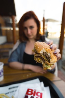 Marupe, Letonya - 22 Nisan 2019: Gün batımında bir tarlada Mcdonalds kahvesi içen genç kadın