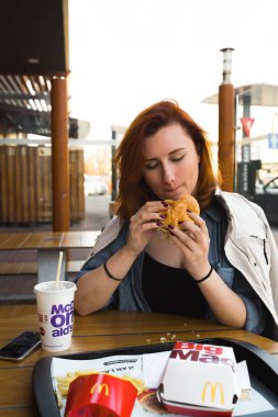 Marupe, Letonya - 22 Nisan 2019: Gün batımında bir tarlada Mcdonalds kahvesi içen genç kadın