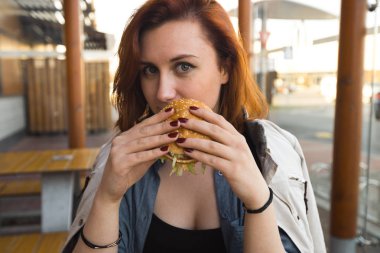 Hamburger yakın - Fast Food Restaurant'ta yemek yiyen Genç Kadın - Cheeseburger, orta boy patates kızartması ve soda