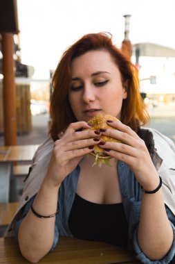 Hamburger yakın - Fast Food Restaurant'ta yemek yiyen Genç Kadın - Cheeseburger, orta boy patates kızartması ve soda