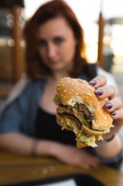 Hamburger yakın - Fast Food Restaurant'ta yemek yiyen Genç Kadın - Cheeseburger, orta boy patates kızartması ve soda