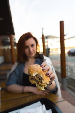 Hamburger yakın - Fast Food Restaurant'ta yemek yiyen Genç Kadın - Cheeseburger, orta boy patates kızartması ve soda