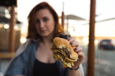Hamburger yakın - Fast Food Restaurant'ta yemek yiyen Genç Kadın - Cheeseburger, orta boy patates kızartması ve soda