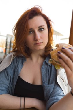 Hamburger yakın - Fast Food Restaurant'ta yemek yiyen Genç Kadın - Cheeseburger, orta boy patates kızartması ve soda