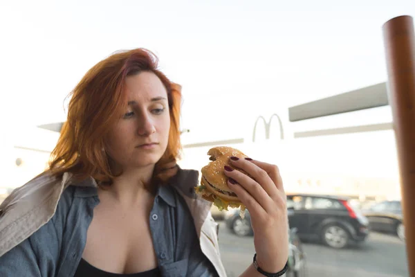 RIGA, Letonia - 22 de abril de 2019: Hamburguesa de cerca - Mujer joven comiendo en el restaurante de comida rápida Mcdonalds - Big Mac, papas fritas medianas y Coca-Cola — Foto de Stock