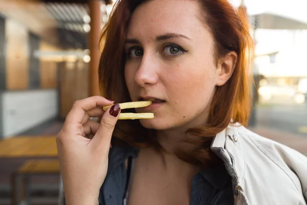 Pommes aus nächster Nähe - Essen und Genießen - junge Frau isst im Fast-Food-Restaurant - Cheeseburger, mittelgroße Pommes und Limo — Stockfoto