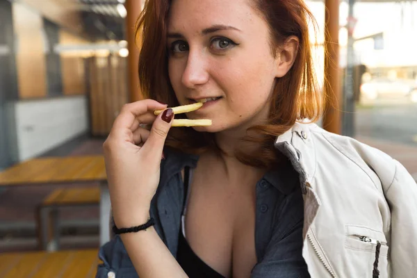 Pá brambory blízko obličeje-jídlo a vychutnávání-mladá žena v restauraci Fast Food-cheeseburger, středně hranolky a soda — Stock fotografie