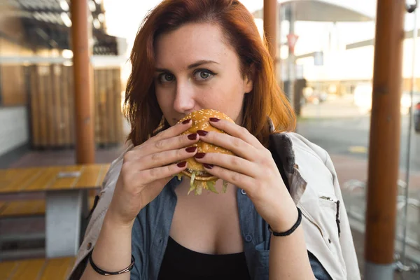 Hamburger yakın - Fast Food Restaurant'ta yemek yiyen Genç Kadın - Cheeseburger, orta boy patates kızartması ve soda