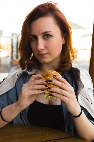 ハンバーガークローズアップ - ファーストフードレストランで食べる若い女性 - チーズバーガー、ミディアムフライドポテト、ソーダ — ストック写真