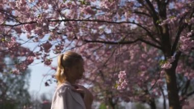 Avrupa 'nın Riga Letonya bölgesinde sakura kiraz çiçeklerinin tadını çıkaran beyaz beyaz kadın.