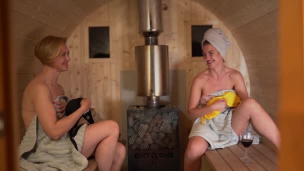 120 fps slow motion van twee vrouwen gooien hun badpak badmode beha bij camera-sexy en hete meisjes dragen alleen handdoeken in een Finse sauna lachen — Stockvideo