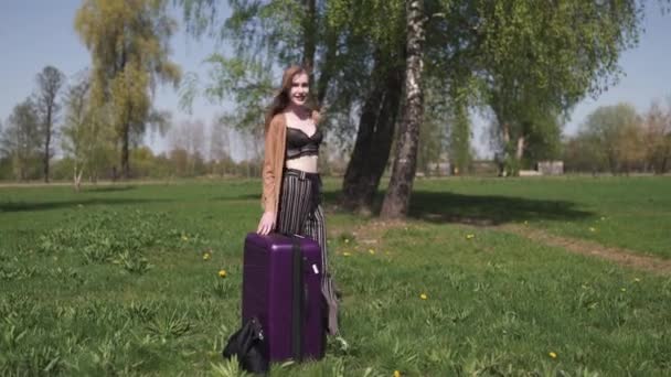 Jeune voyageuse heureuse arrivée dans un nouveau pays de destination - Marcher avec sa valise à bagages - Émotions d'une femme blanche caucasienne aux cheveux longs et légers portant soutien-gorge et veste beige — Video