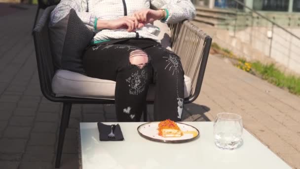 Happy ταξιδευτής τρώγοντας γλυκό επιδόρπιο κέικ σε ένα εστιατόριο-κυματιστά καστανά μαλλιά, λευκό καυκάσιο θηλυκό γυναίκα φορώντας ελαφρύ μπουφάν σε άνοιξη Ηλιόλουστη — Αρχείο Βίντεο