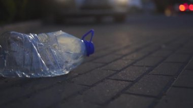 Plastik şişe bir araba önünde gece yerde yatan - Geri dönüşümlü değil dışarı atılmış - Çöp ve şehir ve doğanın kirliliği - Çürümüş çöp