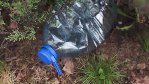 Niebieska duża plastikowa butelka leżąca na ziemi w drzewie w parku leśnym-wyrzucona z recyklingu-Śmietnik i zanieczyszczenie miasta i przyrody-zbutwiałe śmieci — Wideo stockowe