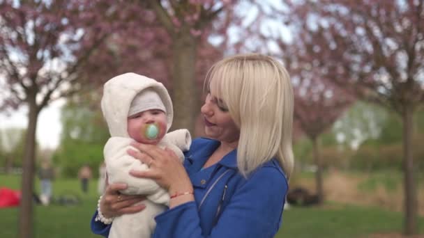 Jonge moeder vrouw genieten van vrije tijd met haar baby jongen kind - Kaukasisch wit kind met een ouders hand zichtbaar - Gekleed in wit overall met harten, moeder in blauw — Stockvideo