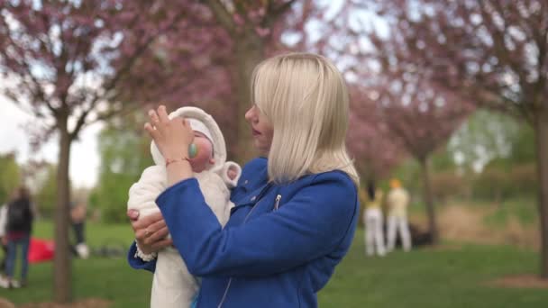 Giovane madre donna godendo il tempo libero con il suo bambino bambino bambino bianco caucasico con una mano dei genitori visibile Vestita in bianco generale con cuori, mamma in blu — Video Stock