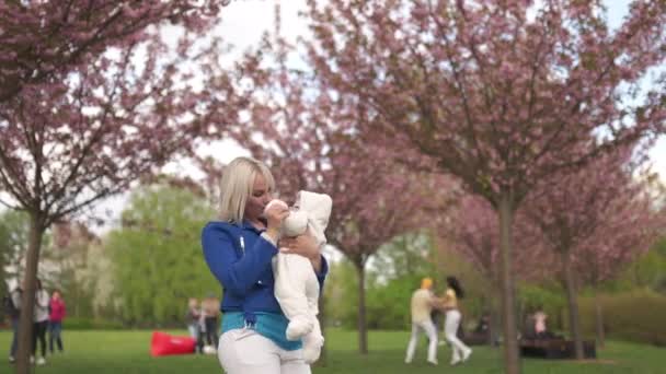 Young mother woman enjoying free time with her baby boy child - Caucasian white child with a parents hand visible - Dressed in white overall with hearts, mom in blue — 图库视频影像