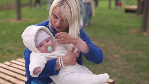 Νεαρή μητέρα γυναίκα απολαμβάνει ελεύθερο χρόνο με το αγοράκι της - Καυκάσιο λευκό παιδί με ορατό το χέρι των γονιών - ντυμένη στα λευκά συνολικά με καρδιές, μαμά στα μπλε — Αρχείο Βίντεο