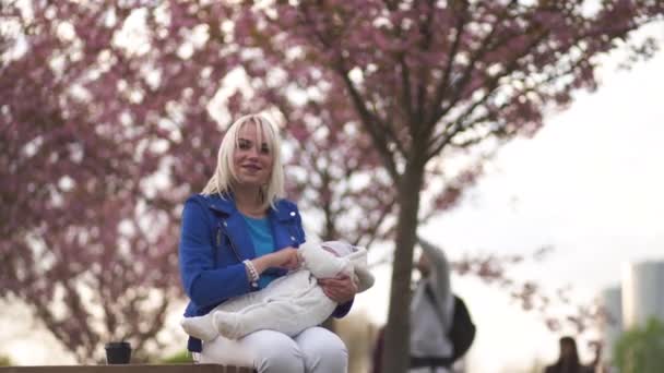 Tânăra mamă se bucură de timp liber cu copilul ei - copil alb caucazian cu o mână vizibilă de părinți - Îmbrăcată în alb, în general, cu inimi, mamă în albastru — Videoclip de stoc