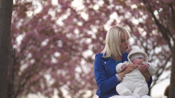 Young mother woman enjoying free time with her baby boy child - Caucasian white child with a parents hand visible - Dressed in white overall with hearts, mom in blue — ストック動画