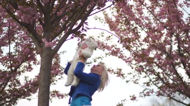 Joven madre mujer disfrutando de tiempo libre con su bebé niño niño blanco caucásico con una mano de los padres visible Vestido de blanco en general con corazones, mamá en azul — Vídeos de Stock