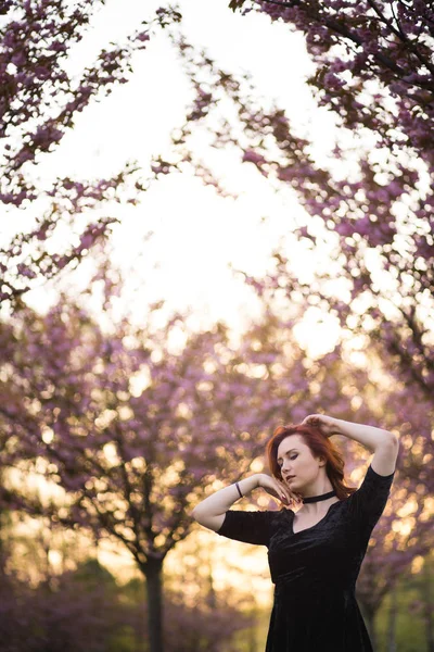 Feliz jovem dançarina de viagens desfrutando de tempo livre em um parque de flores de cerejeira sakura - menina ruiva branca caucasiana - Vestida de chocker preto, vestido preto e golfs pretos — Fotografia de Stock