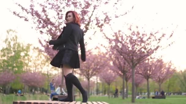 Šťastná mladá cestovní tanečnice žena, která si užívá volného času v kvetoucí partě Sakura-Kavkazská bílá rusovitá dívka-oblečený černý šocker, černé šaty a černé Golf — Stock video
